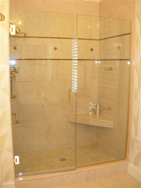 An Over Sized Shower Stall With A Corner Seat And Marble And Glass Tile