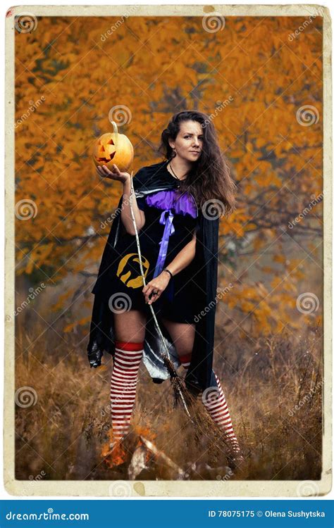 Young Woman In Halloween Witch Costume In The Autumn Forest With Yellow