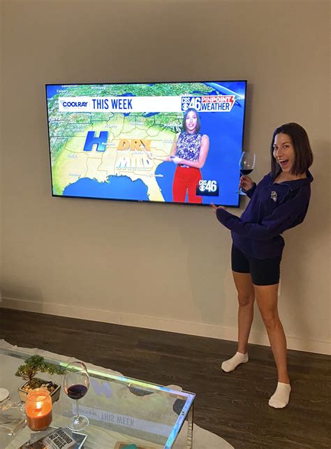 A Woman Standing In Front Of A Tv Holding A Wine Glass