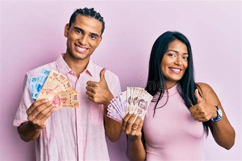Young Latin Couple Holding Mexican Pesos Smiling Happy And Positive