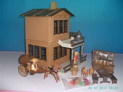 A Toy Horse Drawn Carriage In Front Of A Wooden Doll House With Other