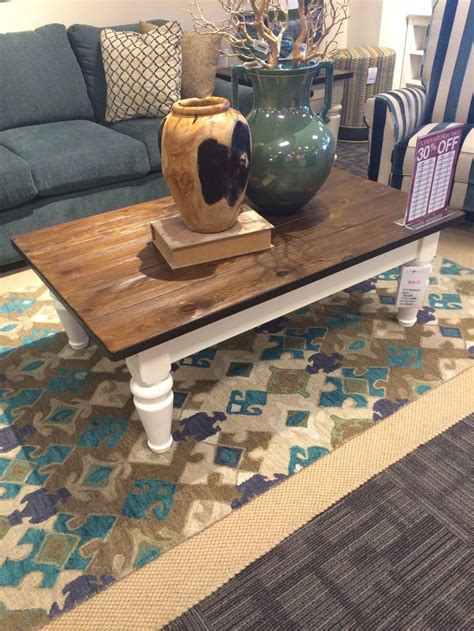 A Coffee Table With Two Vases Sitting On Top Of It Next To A Couch