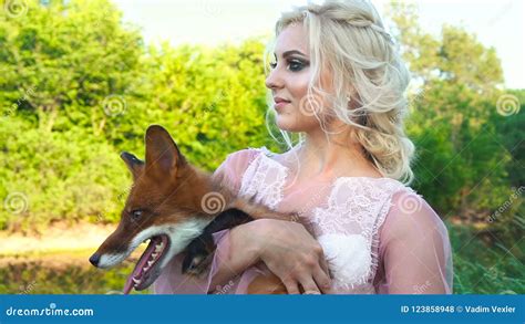 A Girl Is Holding Her Fox In Her Arms The Foxes Is Licked Stock