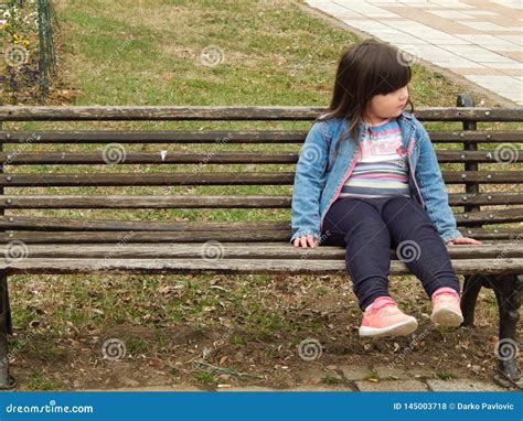 A Little Girl Sitting On A Park Bench Stock Photo Image Of Sits