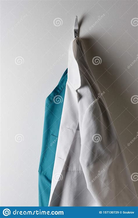 Doctors White Lab Coat And Green Scrubs Hanging On A Hook Stock Image