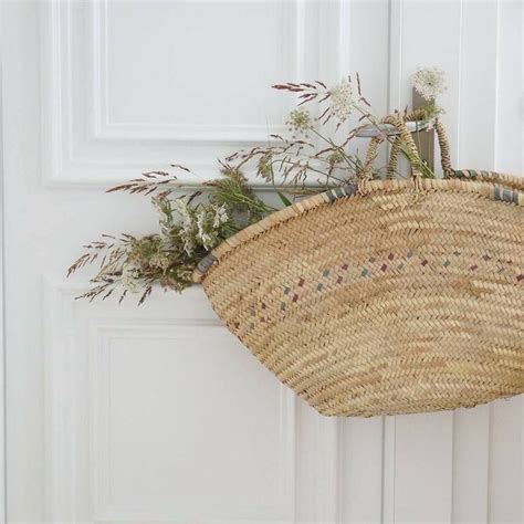 A Wicker Basket Hanging On The Front Door With Plants In It And An Iron