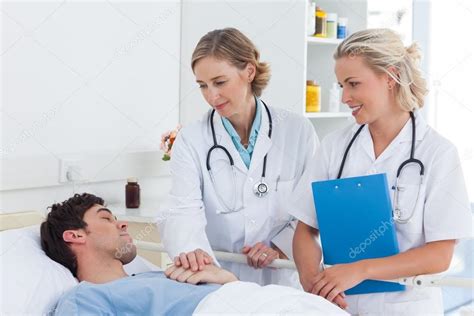 Dos Doctores Atendiendo A Un Paciente Fotografía De Stock © Wavebreakmedia 25727059