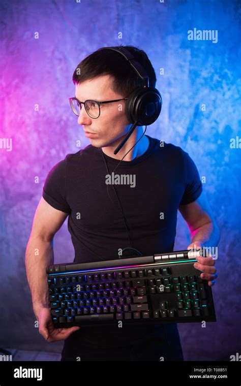 Professional Boy Gamer Holding Gaming Keyboard Over Colorful Pink And