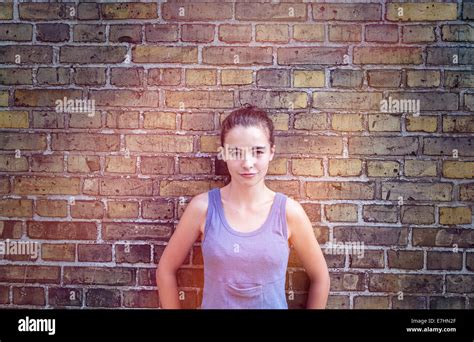 Portrait Of A Sulking Teenager Girl Leaning Against A Brick Wall Stock