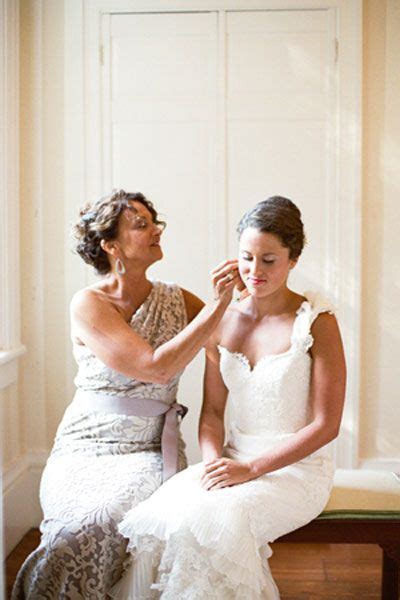 Two Women Sitting Next To Each Other In Front Of A Window And One Is Fixing The Brides Hair