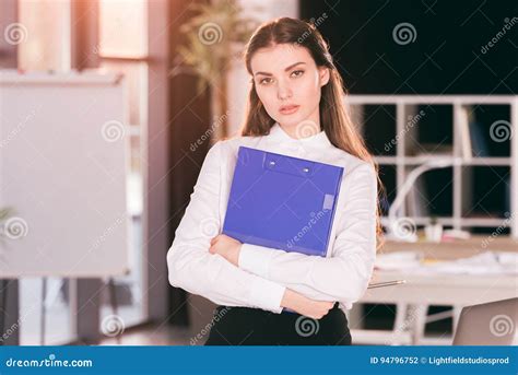 Businesswoman Holding Clipboard While Standing In Modern Office Stock