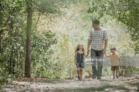 Hispanic Father Walking Son And Daughter In Woods Photo Getty Images