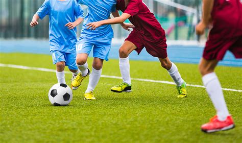 Young soccer players running towards soccer ball. Football soccer game
