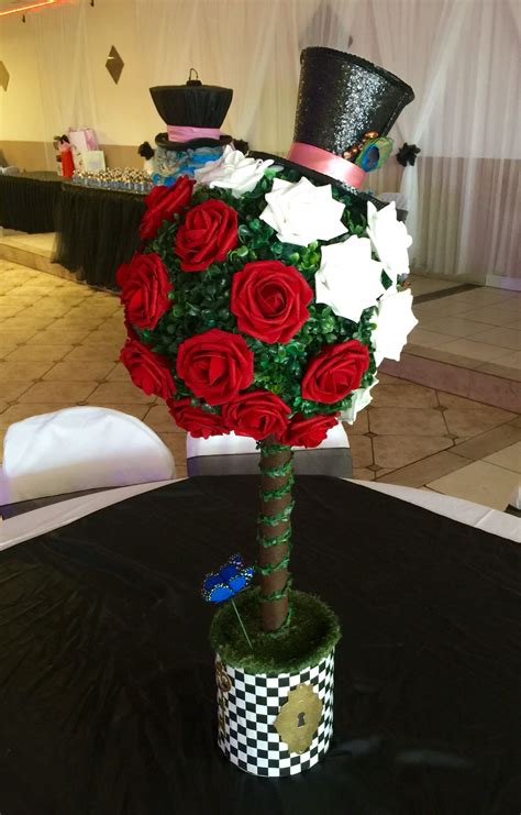 A Top Hat With Red Roses And Green Stems In A Vase On A Black Table Cloth