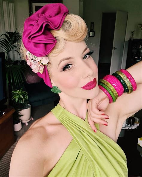 A Woman In A Green Dress With Pink Flowers On Her Head And Bracelets