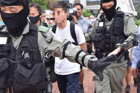 警官に連行される若者。逮捕されて後手に手錠をかけられていた。 写真｜【西日本新聞me】