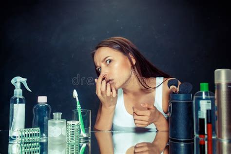 Unsatisfied Young Woman Looking At Her Self In Mirror On Black