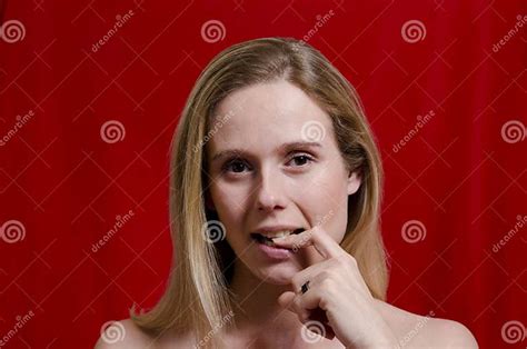 Young Blonde With Finger In Her Mouth On Red Background Stock Image