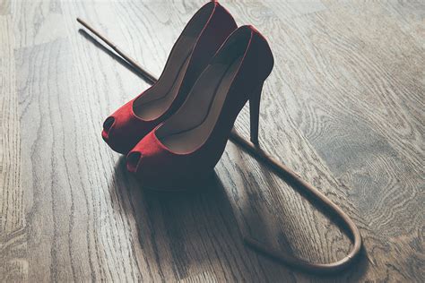 woman red high heel shoes and rattan school cane strict domination bdsm concept photograph by