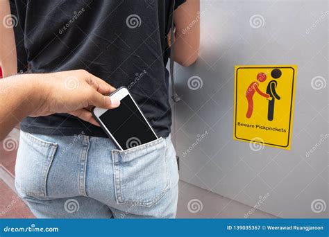 thief stealing mobile phone from back pocket of a woman with beware pickpockets sign symbol