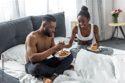 African American Couple Eating Pancakes In Bedroom Buy This Stock