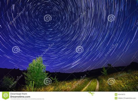 Alone Tree On Night Sky With Stars Startrails And Country Road Stock