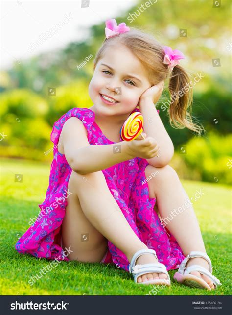 Photo Of Cute Little Girl Sitting On Green Grass On Backyard And