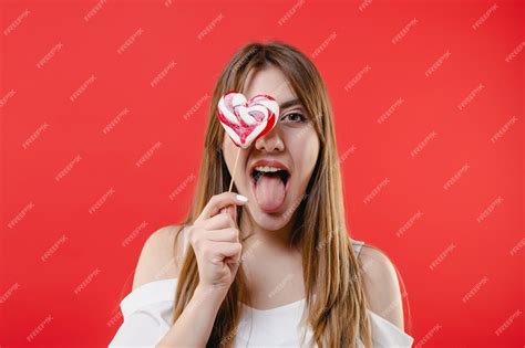 Premium Photo Sexy Woman Covering Eye With Heart Shaped Lollypop Candy Wearing White Blouse