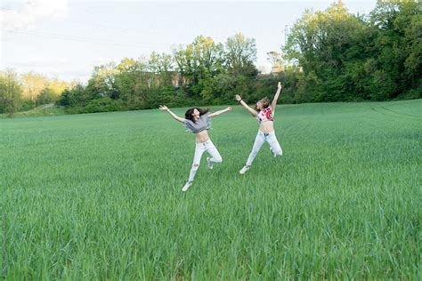 Teenagers Jumping In The Green Grass By Stocksy Contributor Beatrix