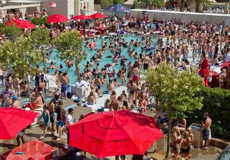 Many People Are In The Pool With Red Umbrellas