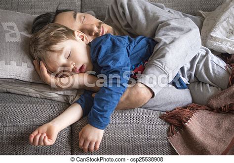 Father And Son Napping On The Couch Portrait Of Father And Son Fallen Asleep Together On The