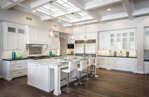 Luxury Open Plan Kitchen With White Cabinets Marble Countertops Subway Tile Backsplash And Wood Flooring 