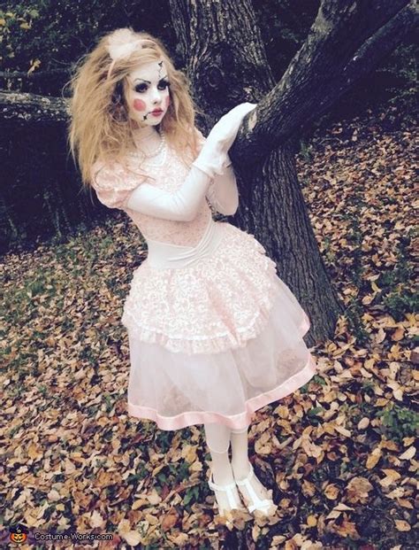 A Woman Dressed Up As A Zombie Holding Onto A Tree In The Woods With Leaves All Around Her