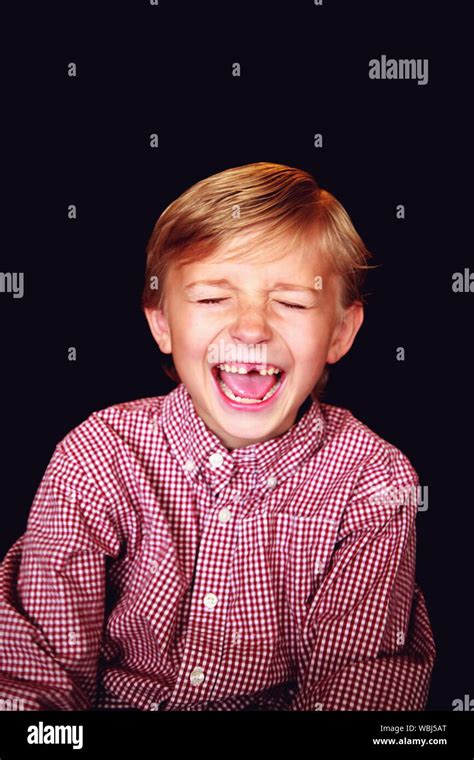 Boy Laughing With Eyes Closed Against Black Background Stock Photo Alamy