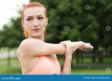 Attractive Redhead Girl Stretching Her Arm And Shoulder In The Park
