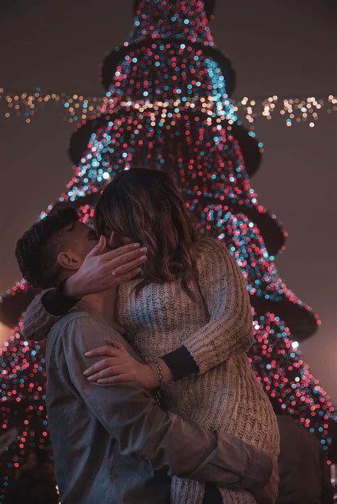 Download Christmas Couple Kissing Against Tree Picture