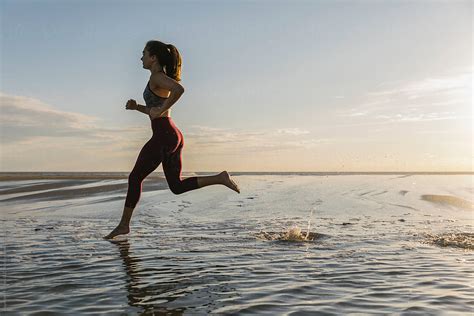 Beautiful Fit Female Athlete Running On Remote Beach By Stocksy Contributor Raymond Forbes