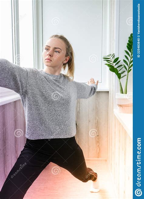 Young Millennial Blonde Woman Doing Yoga Exercise Stretching Fitness At Balcony Home