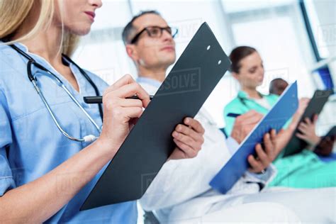 Cropped Shot Of Nurse Writing In Clipboard On Conversation Stock