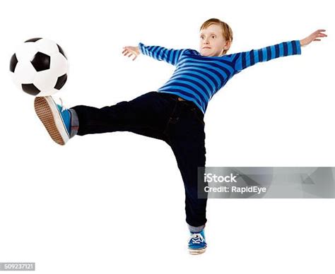 Balancing Act As Schoolboy Footballer Kicks Ball Leaning Backwards