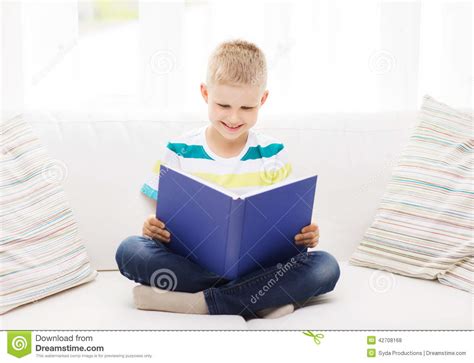 Het Glimlachen Van Weinig Boek Van De Jongenslezing Op Laag Stock Foto