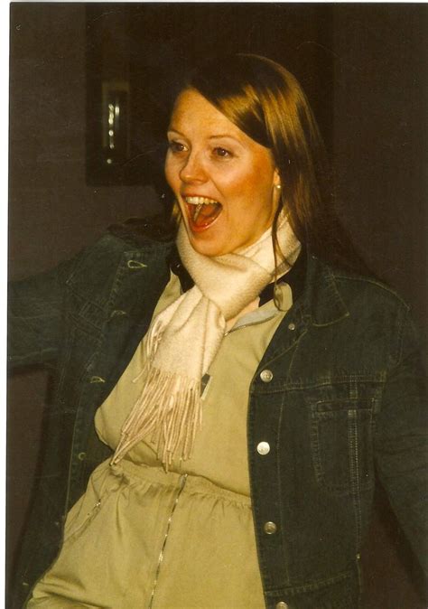 a woman with her mouth wide open wearing a scarf and jacket posing for the camera