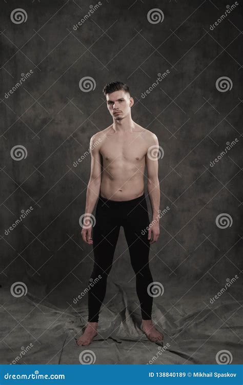 A Young Male Ballet Dancer With Black Leggings And A Naked Torso Performs Dance Moves Against A