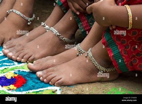 indian girls bare feet around a indian rangoli peacock festival design made in coloured powder