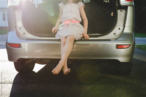 Girl In Dress Letting Her Bare Legs Dangle From Back Of A Car By