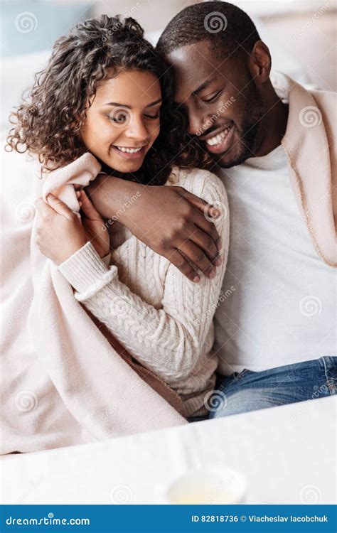 Delighted Young African American Couple Sitting And Hugging Stock Photo