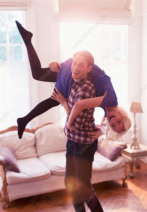 Husband Carrying Wife Over Shoulder In Living Room Stock Image F016