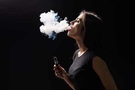 Joven Y Bella Mujer Morena Fumando Vaping Cigarrillo Electrónico Con Humo En La Pared Negra