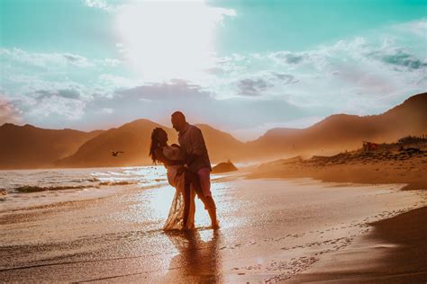 Happy Romantic Couple Holding Each Other On A Sand Beach During Sunset