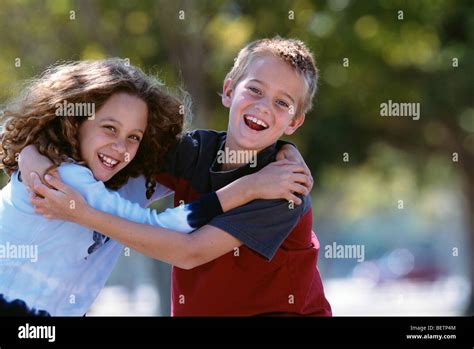 Young Girl And Boy Smiling Hugging Each Other Outdoors Stock Photo Alamy